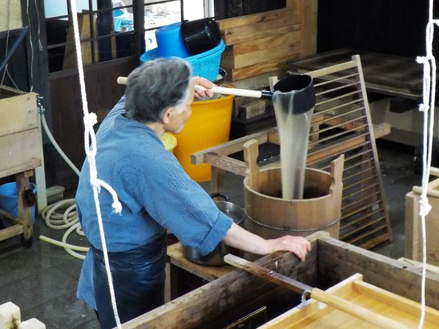 柄杓ですくった粘りのあるネリが容器へ流れ落ちる様子