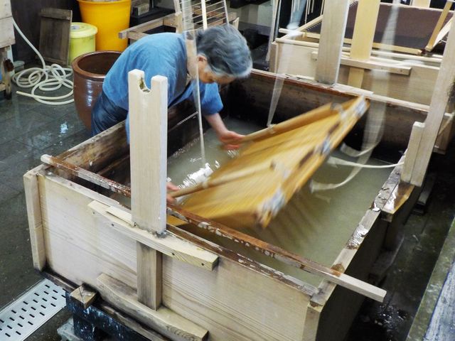 卯立の工芸館で大きな漉き桁を動かして紙を漉く様子