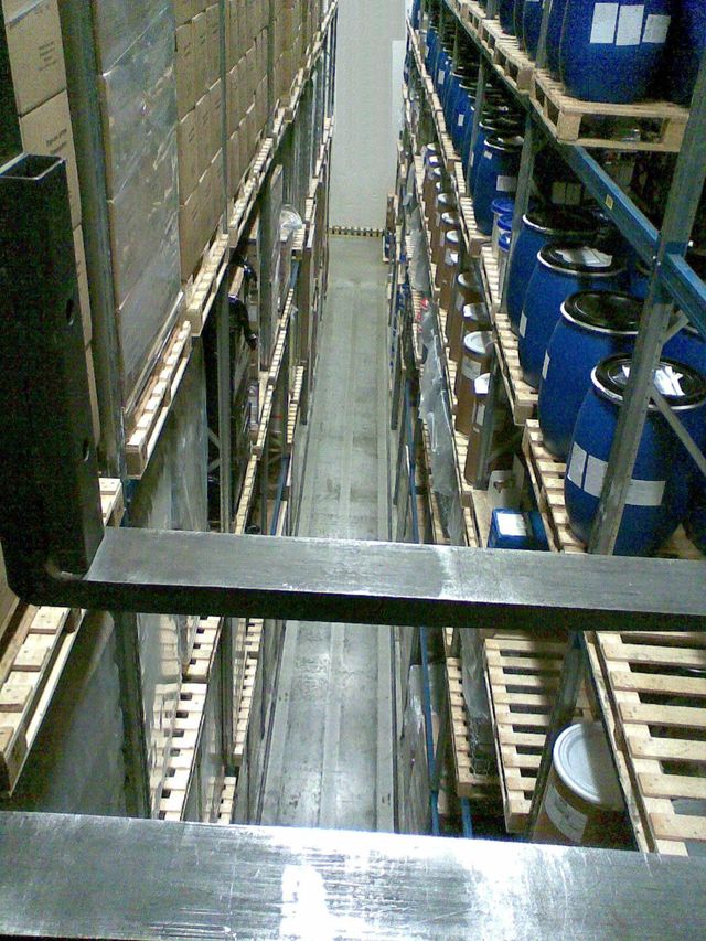高いパレット棚に段ボール箱やドラム缶が保管された倉庫