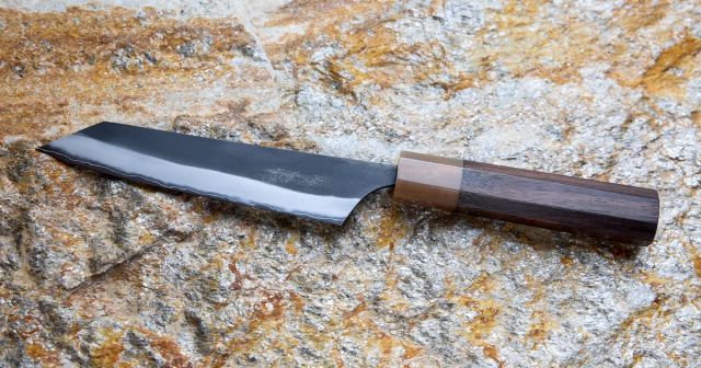 石の上に置かれた、黒い刃と木製の柄を持つMasashi Kokuenのペティナイフ