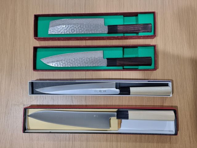 牛刀、柳刃、三徳、菜切の4本の和包丁が木の台の上に並べられている