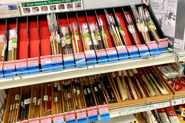 文具店の棚に並ぶ、値札のついた多数の書道用の筆