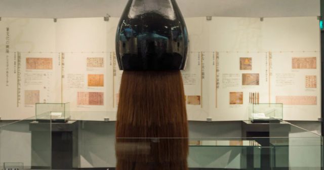 筆の里工房に展示された巨大な筆の穂首と、背景の展示ケース