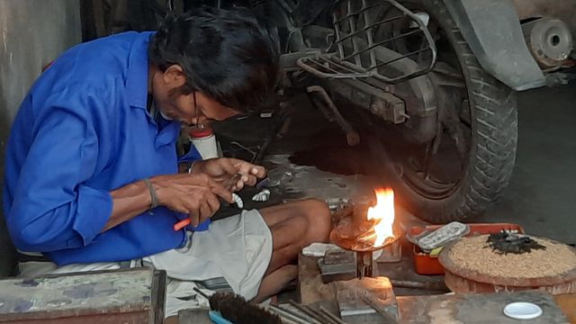 火を使う作業台で貴金属を加工する職人