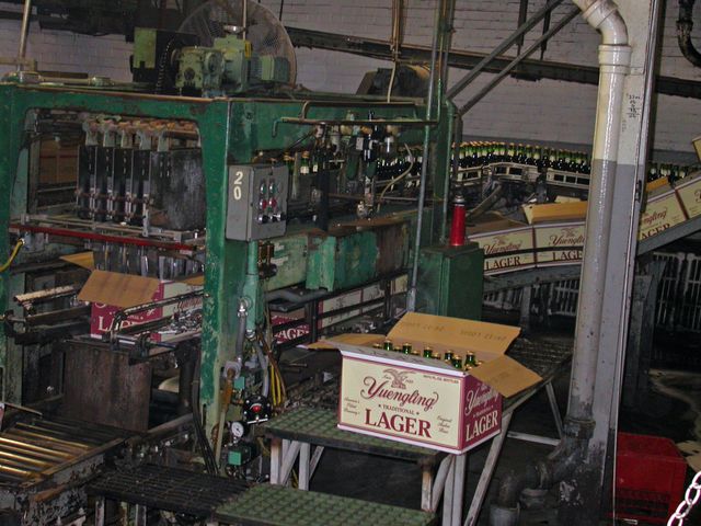 瓶と段ボール箱がコンベヤで運ばれるビール工場の箱詰め設備