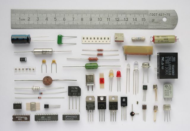 定規の下に抵抗器やコンデンサなど形の異なる電子部品が並ぶ