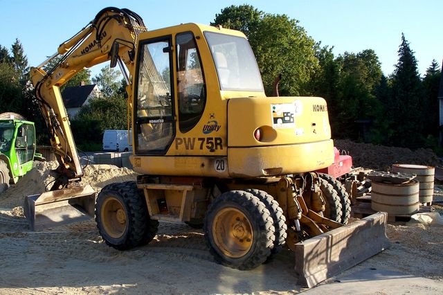 ドイツの道路脇に置かれた黄色いコマツPW75Rホイール式油圧ショベル