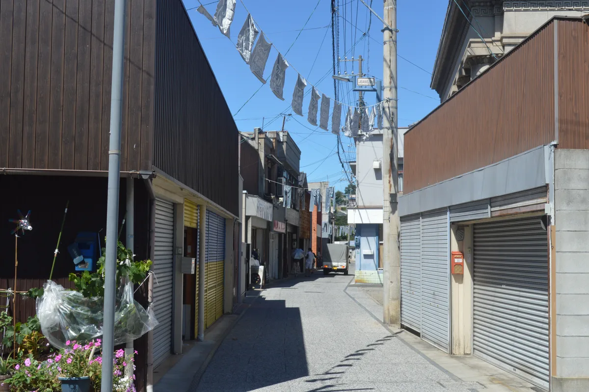 建物の間にジーンズが吊られた児島ジーンズストリートの通り