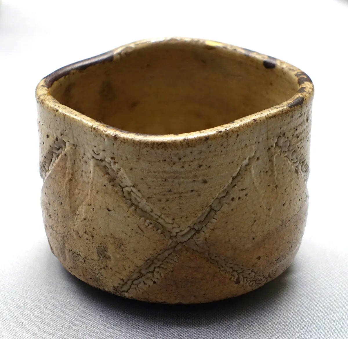 表面に交差する彫り文様がある、茶色い唐津焼の茶碗