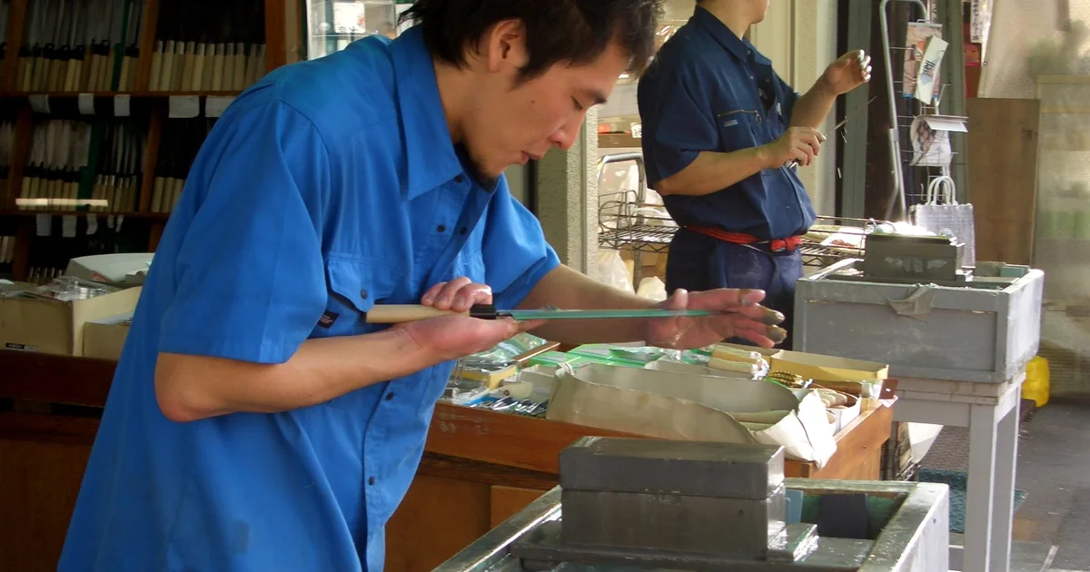 築地市場で包丁の刃を手元で確かめる作業者と砥石